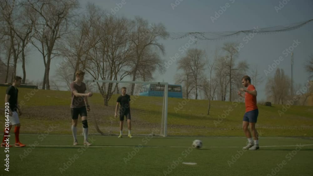 Football team playing soccer on sports field during football training session. Soccer players exercising ball control, dribbling and shots while training together on football pitch in springtime. Football team playing soccer on sports field during football training session. Soccer players exercising ball control, dribbling and shots while training together on football pitch in springtime.