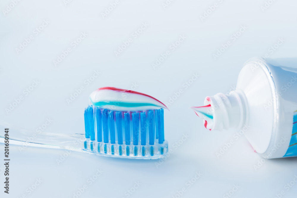 toothbrush of clear plastic with blue bristles, white blue red toothpaste squeezes out of a tube toothbrush of clear plastic with blue bristles, white blue red toothpaste squeezes out of a tube