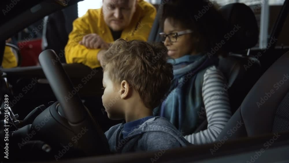 Black woman with boy sitting in car and exploring it with man and consultant outside while considering purchase in dealer shop. Black woman with boy sitting in car and exploring it with man and consultant outside while considering purchase in dealer shop.