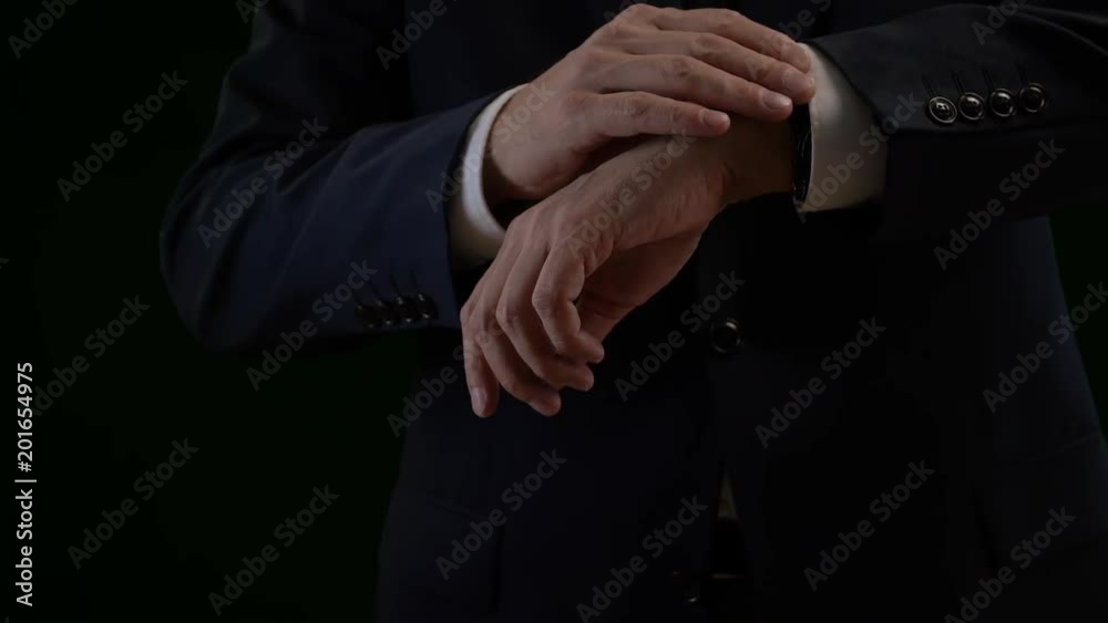 Close up of business man looking on watch and fixing suit Close up of business man looking on watch and fixing suit