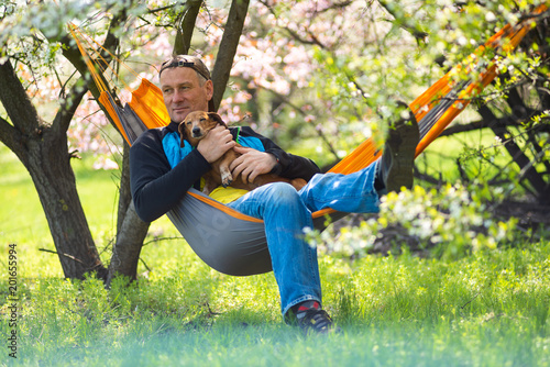 Happy man with his funny dog dachshund relaxes in a hammock