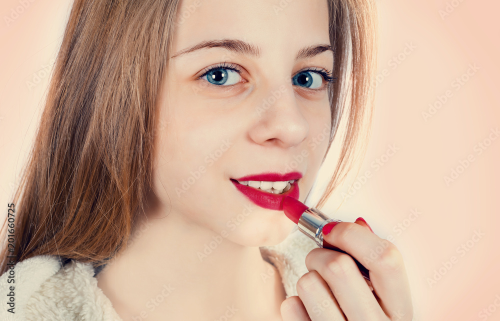 A beautiful girl is applying lipstick to her lips A beautiful girl is applying lipstick to her lips