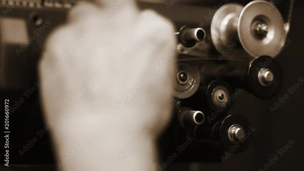 Man Loading the Reel of the Film to the Movie Projector. Sepia Tone.
