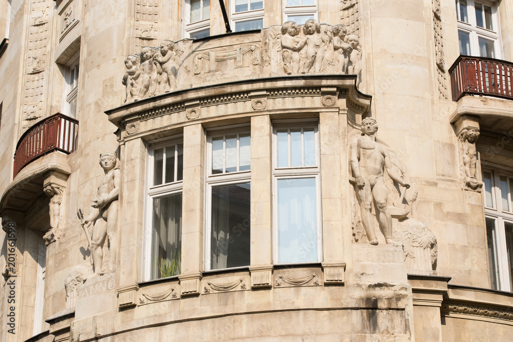 Element of an old building with a window and balconies, decorated with bas-reliefs and sculptures