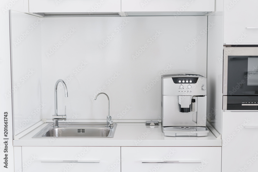 Metal chrome sink with two taps, plain and filtered water. Fragment of modern kitchen with counter and sink. Detail of interior apartment.