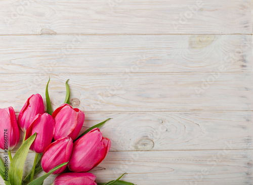 Bouquet of pink tulips on a light wooden background. View from above.