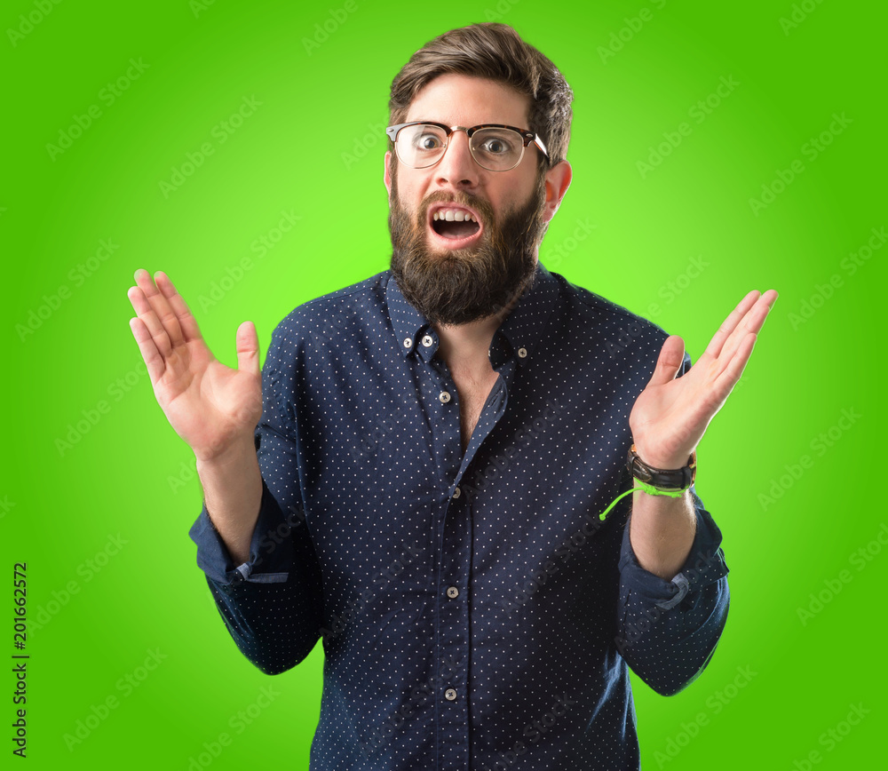 Young hipster man with big beard happy and surprised cheering expressing wow gesture over green background Young hipster man with big beard happy and surprised cheering expressing wow gesture over green background