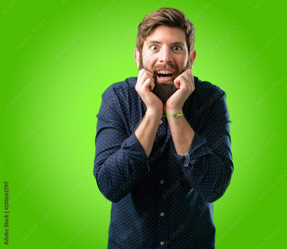Young hipster man with big beard happy and surprised cheering expressing wow gesture over green background Young hipster man with big beard happy and surprised cheering expressing wow gesture over green background