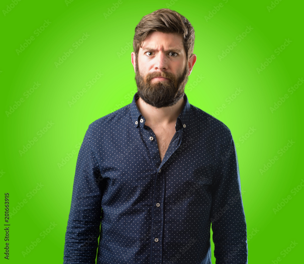 Obraz premium Young hipster man with big beard making funny face fooling over green background