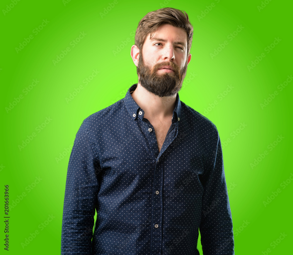 Fototapeta premium Young hipster man with big beard making funny face fooling over green background