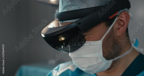 CU Portrait of surgeon using augmented reality holographic hololens headset while operating in modern operation theater. 4K UHD 60 FPS SLO MO photo