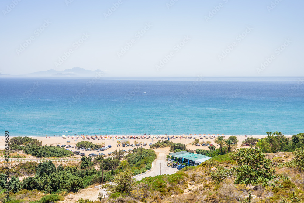Beautiful sunny coast view to the greek mediterranean blue sea with crystal clear water and pure sandy beach empty place with some mountains rocks surrounded, Kefalos, Kos Island, Dodecanese, Greece Beautiful sunny coast view to the greek mediterranean blue sea with crystal clear water and pure sandy beach empty place with some mountains rocks surrounded, Kefalos, Kos Island, Dodecanese, Greece