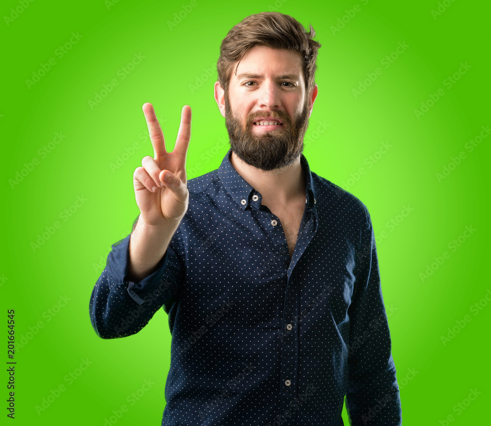 Young hipster man with big beard raising his fingers, number two over green background Young hipster man with big beard raising his fingers, number two over green background