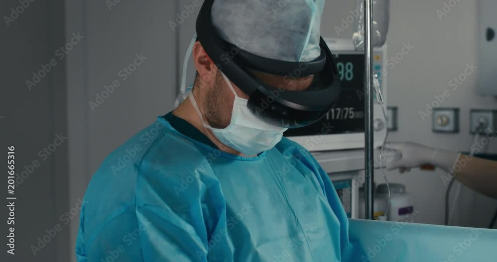 CU Portrait of surgeon using augmented reality holographic hololens headset while operating in modern operation theater. 4K UHD 60 FPS SLO MO CU Portrait of surgeon using augmented reality holographic hololens headset while operating in modern operation theater. 4K UHD 60 FPS SLO MO