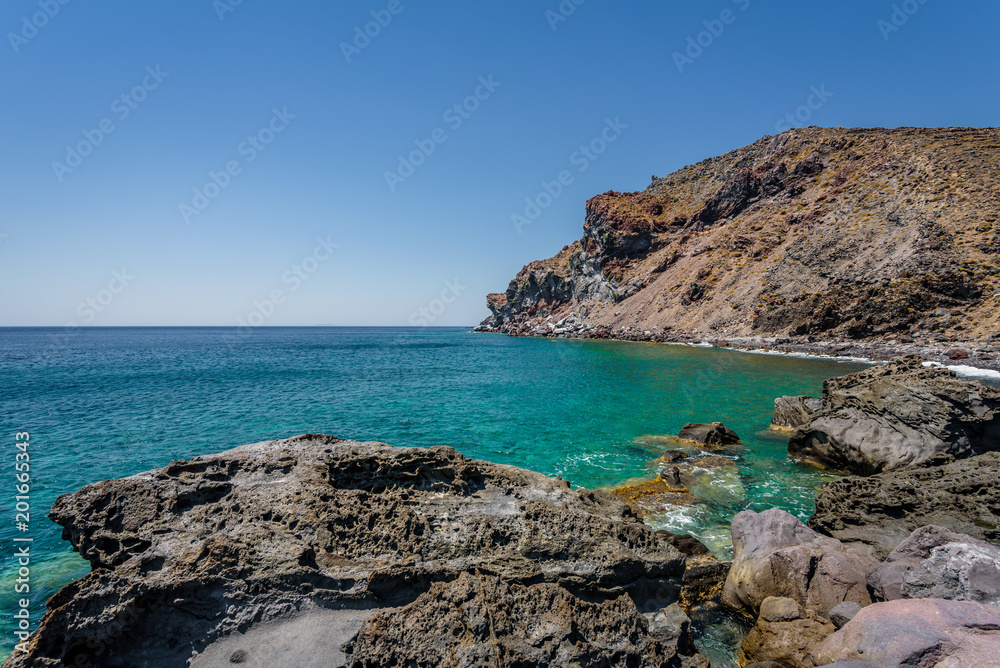 Sunny beautiful summer coast view to the greek blue sea with shallow clear water and small volcano rocks at empty shore escape relax swim, Avlaki Beach, Nisyros Island, Kos, Dodecanese, Greece