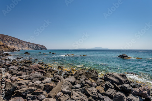 Sunny beautiful summer coast view to the greek blue sea with shallow clear water and small volcano rocks at empty shore escape relax swim, Avlaki Beach, Nisyros Island, Kos, Dodecanese, Greece