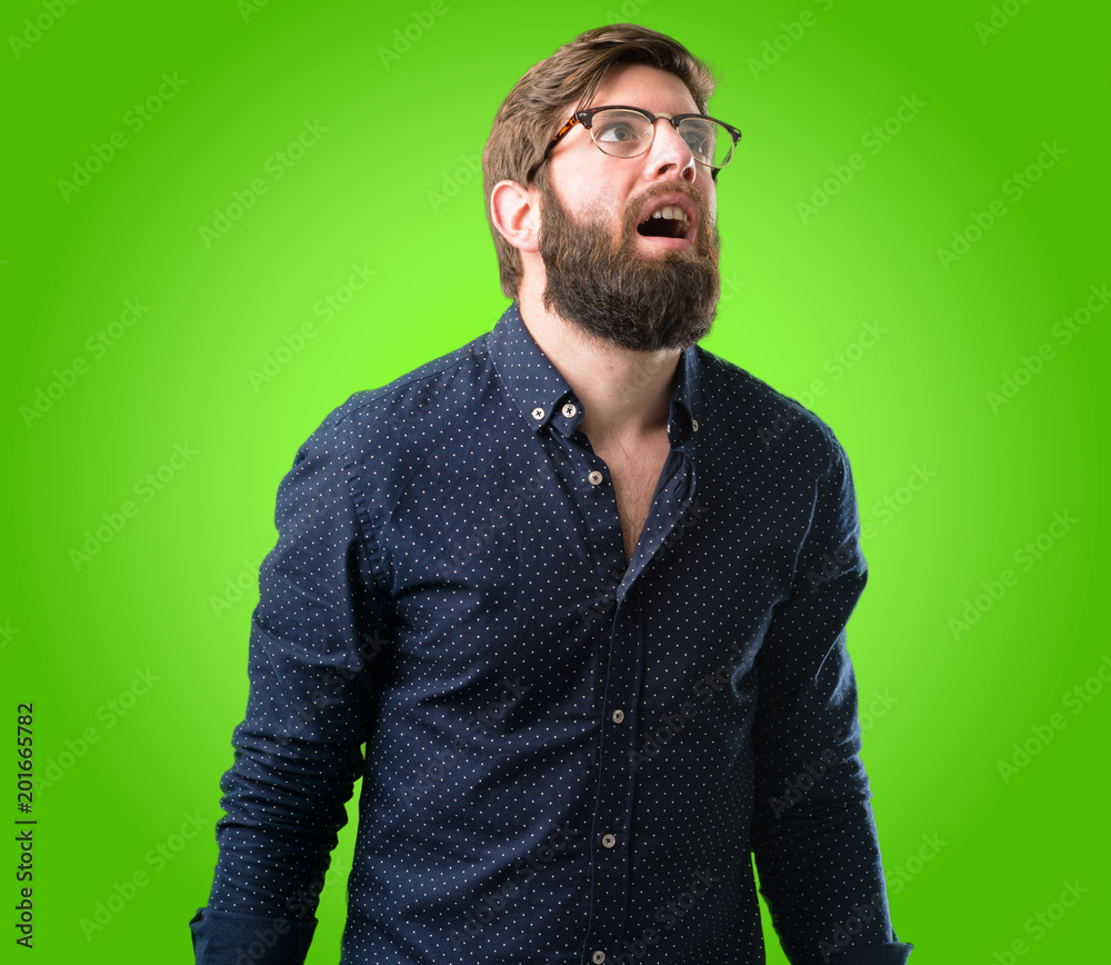 Young hipster man with big beard happy and surprised cheering expressing wow gesture over green background Young hipster man with big beard happy and surprised cheering expressing wow gesture over green background