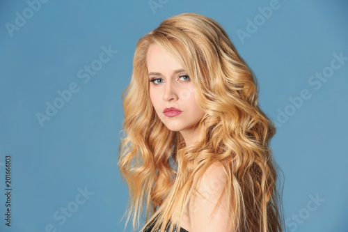 Beautiful young woman with long wavy hair on color background © Africa Studio