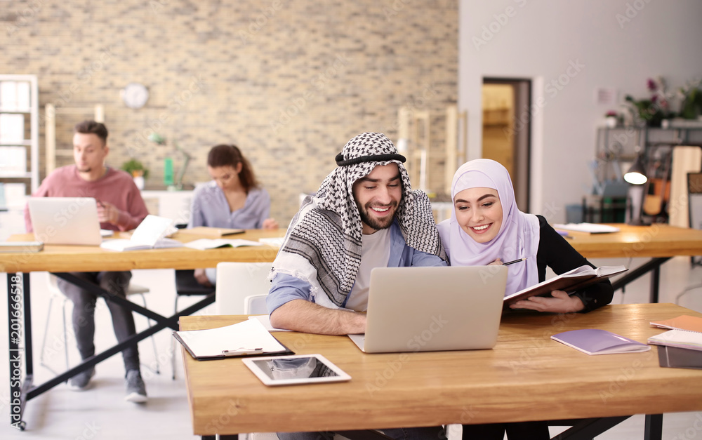 Fototapeta premium Muslim students in traditional clothes studying indoors
