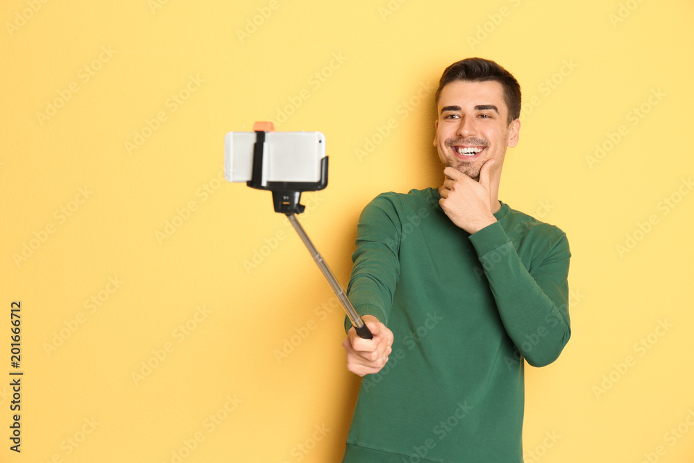 Young handsome man taking selfie against color background Young handsome man taking selfie against color background