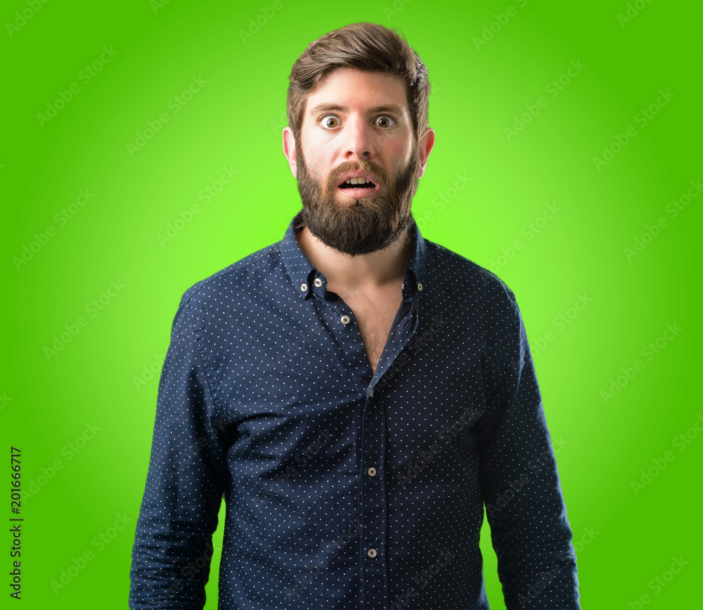Obraz premium Young hipster man with big beard happy and surprised cheering expressing wow gesture over green background