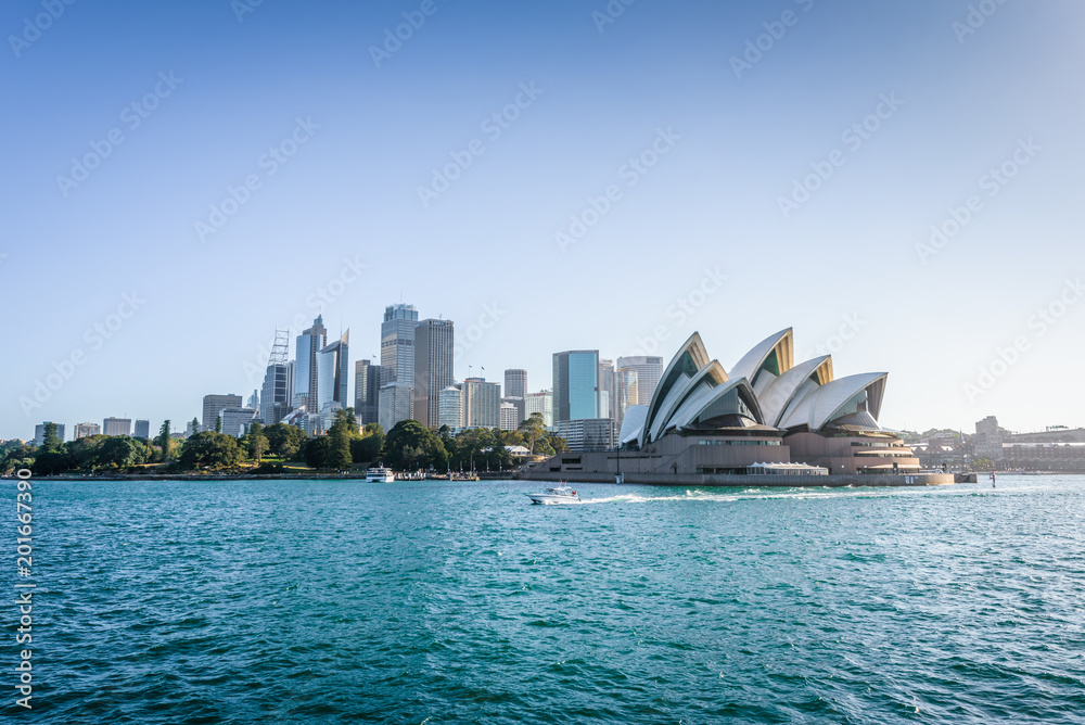 Naklejka premium Piękne słoneczne wybrzeże z widokiem na Skyline i słynną Operę w jasny ciepły dzień, rejs promem z mostu portowego do Manly City, Opera House and Quay, Sydney, NSW / Australia - 10 12 2017