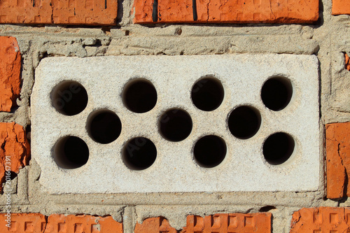 Fotografie A white hollow silicate brick embedded in a wall of red brick