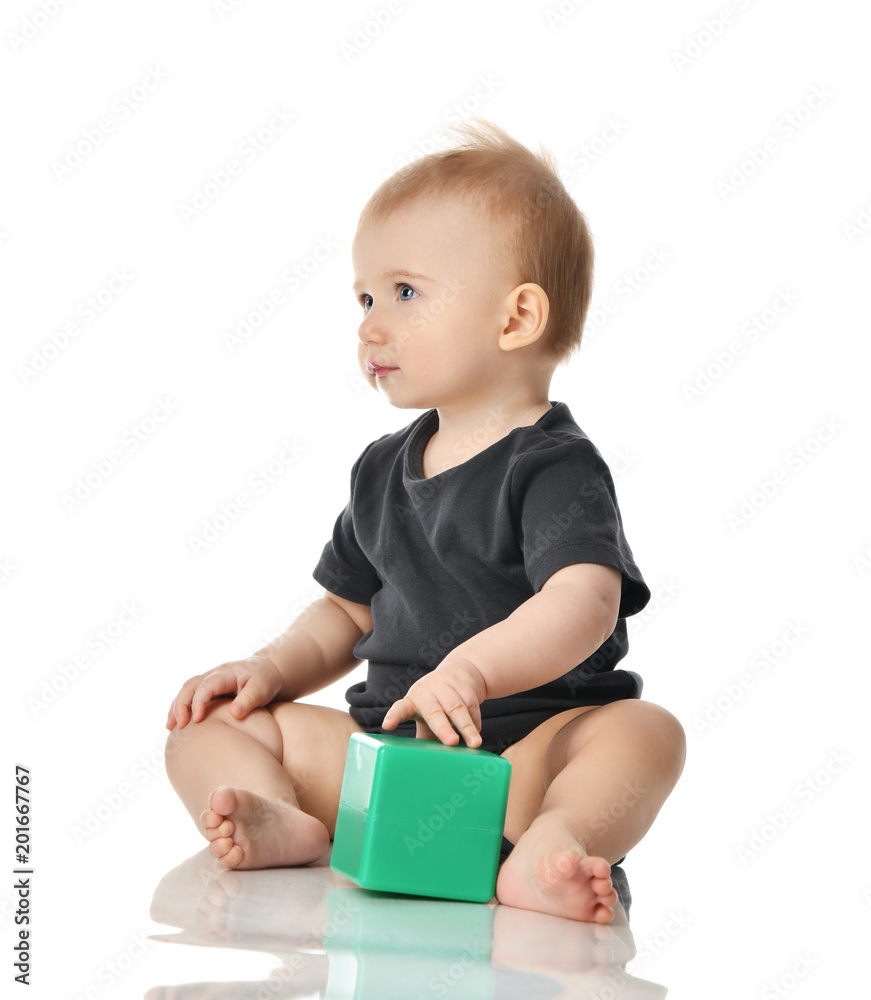 Infant child baby toddler sitting playing with green brick toy isolated on a white Infant child baby toddler sitting playing with green brick toy isolated on a white