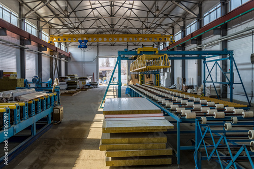 Thermal insulation sandwich panel production line. Machine tools  roller conveyor and gantry crane in workshop