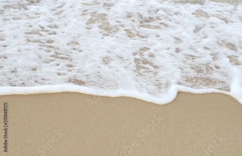 The white waves bounce up to the fine sand.