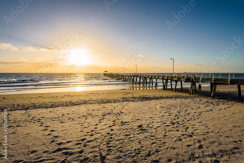 Beautiful colorful sunset summer view to the calm great ocean with pure sandy beach and a lovely empty wooden jetty lighten the night at a public boulevard  Glenelg Jetty  Adelaide  South  Australia