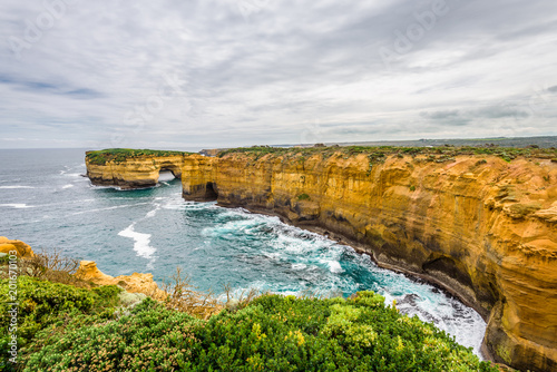 Cloudy sunny summer coast view to a beautiful sandy beach bay and rocky erosion sand limestone cliff of Great Ocean Road, walking at Loch Ard Gorge, Port Campbell National Park, Victoria/ Australia