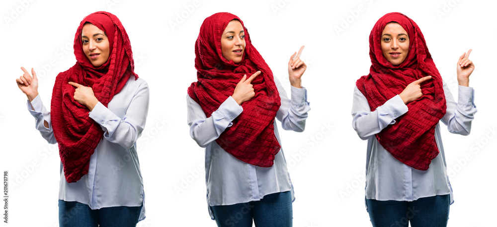 Fototapeta premium Arab woman wearing hijab pointing away side with his finger isolated over white background