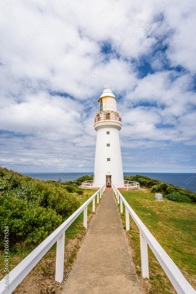 Sunny beautiful summer coast view a white bright light station at Otway National Park with green area and the blue waves of the Bass Strait sea, Cape Otway Lighthouse, Victoria, Melbourne, Australia