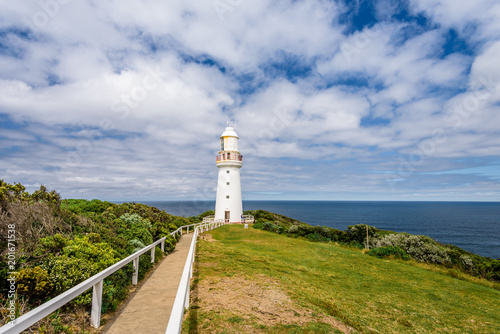 Sunny beautiful summer coast view a white bright light station at Otway National Park with green area and the blue waves of the Bass Strait sea, Cape Otway Lighthouse, Victoria, Melbourne, Australia photo
