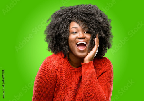 Beautiful african woman so happy and confident showing a big smile surprised finger