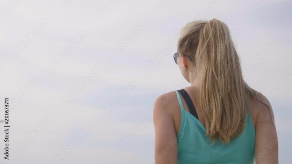 Young woman raising hands up watching at sky with plane,airplane passing overhead, young happy girl watching waving and jumping. Happiness, freedom and vacation concept. Young woman raising hands up watching at sky with plane,airplane passing overhead, young happy girl watching waving and jumping. Happiness, freedom and vacation concept.