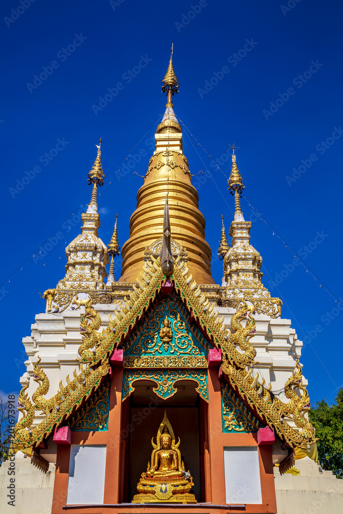 Fototapeta premium Golden light shining on white and gold pagoda during sunrise / sunset with blue sky in Mae hong son Thailand