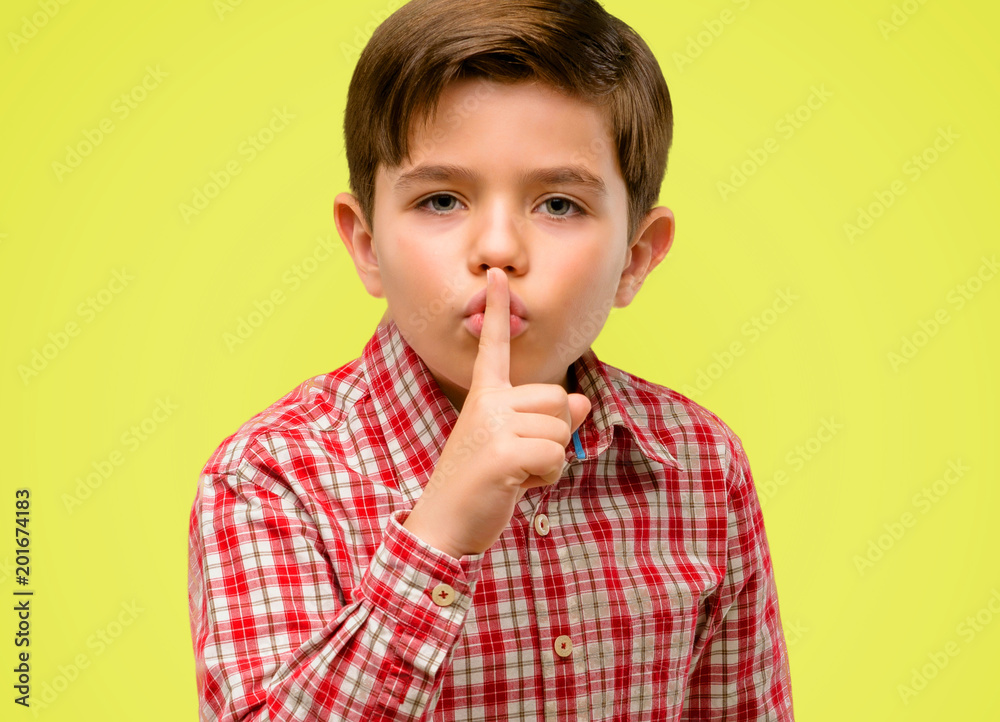 Handsome toddler child with green eyes with index finger on lips, ask to be quiet. Silence and secret concept over yellow background Handsome toddler child with green eyes with index finger on lips, ask to be quiet. Silence and secret concept over yellow background