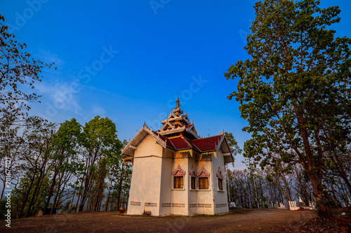 Golden light shining on white and gold pagoda during sunrise / sunset with blue sky in Mae hong son Thailand