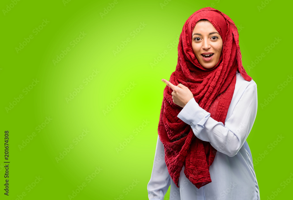 Young arab woman wearing hijab pointing away side with finger Young arab woman wearing hijab pointing away side with finger