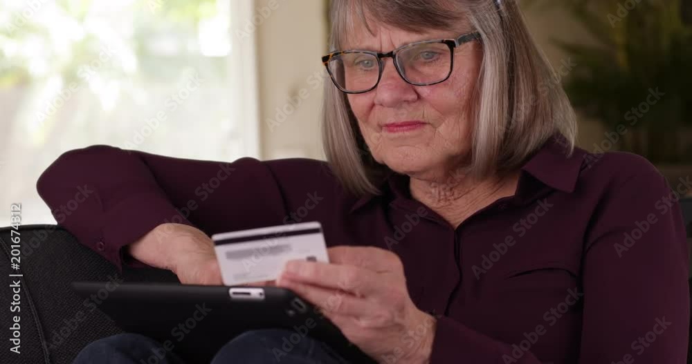 Close-up of joyful senior woman making online purchase using tablet indoors, Tight shot of happy retired woman making internet payment with credit card, 4k Close-up of joyful senior woman making online purchase using tablet indoors, Tight shot of happy retired woman making internet payment with credit card, 4k
