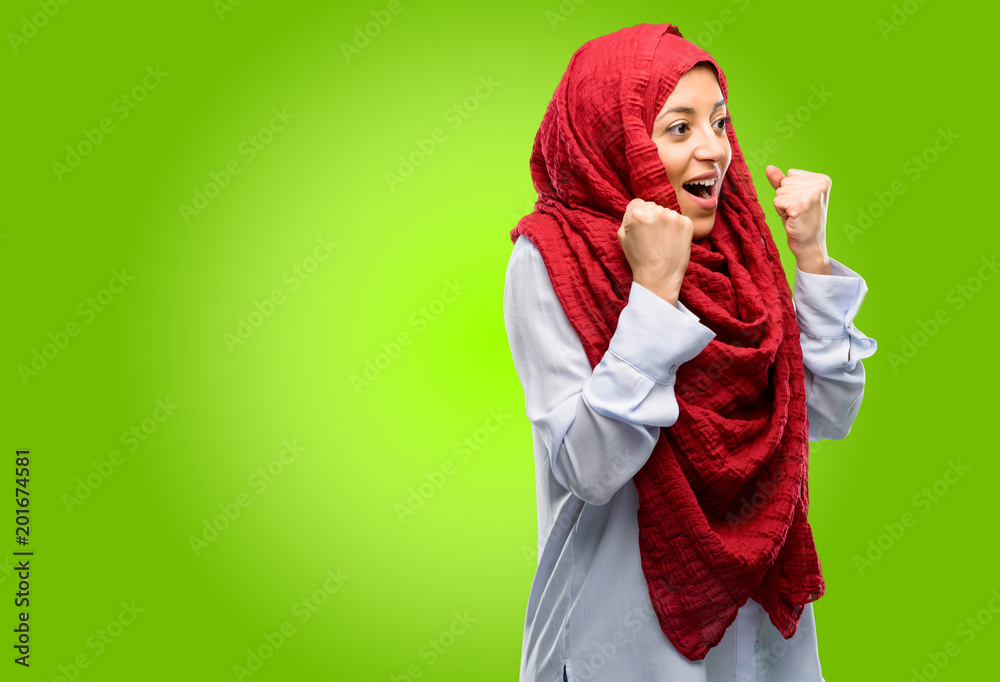 Young arab woman wearing hijab happy and excited expressing winning gesture. Successful and celebrating victory, triumphant Young arab woman wearing hijab happy and excited expressing winning gesture. Successful and celebrating victory, triumphant