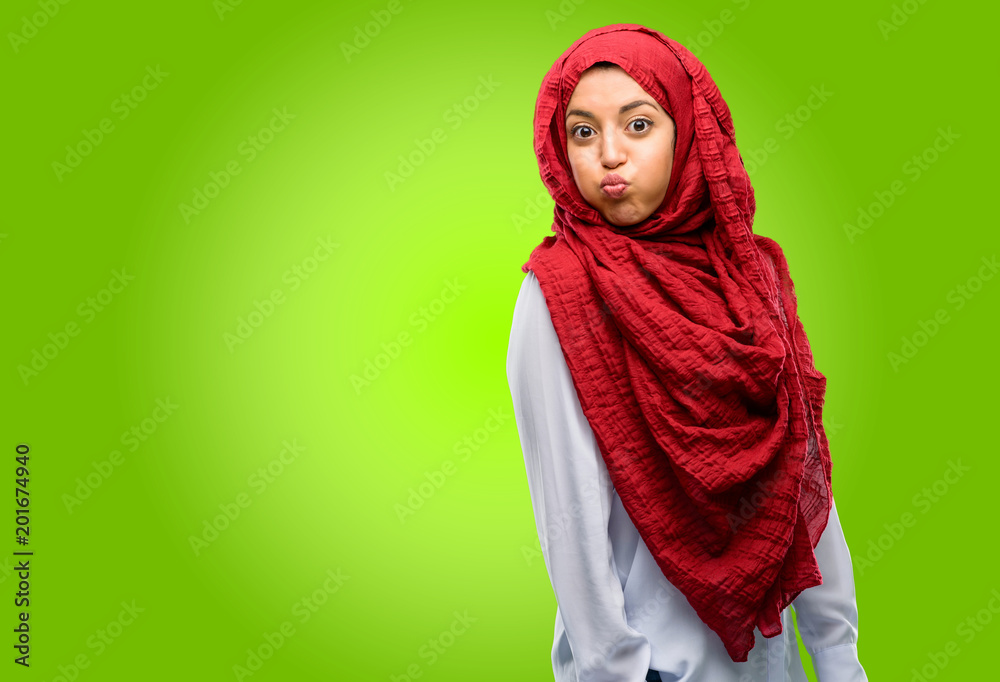 Young arab woman wearing hijab puffing out cheeks, having fun making funny face Young arab woman wearing hijab puffing out cheeks, having fun making funny face