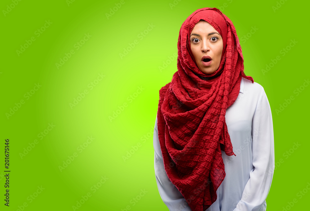 Young arab woman wearing hijab scared and surprised cheering expressing wow gesture. Unbelieving Young arab woman wearing hijab scared and surprised cheering expressing wow gesture. Unbelieving