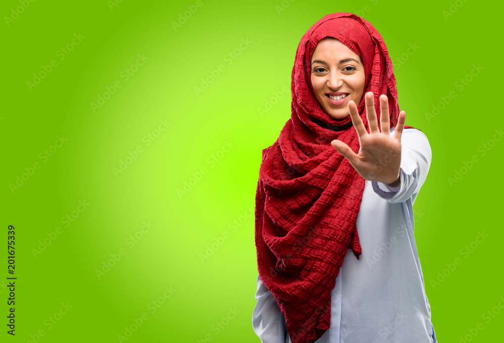 Young arab woman wearing hijab raising his finger, is the number five