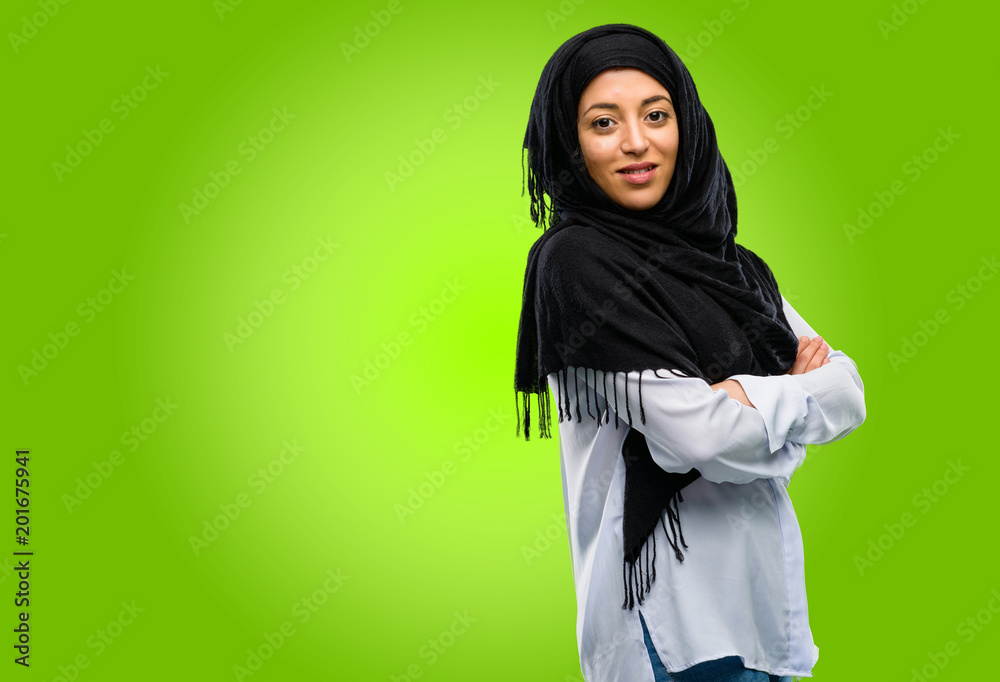 Young arab woman wearing hijab with crossed arms confident and happy with a big natural smile laughing Young arab woman wearing hijab with crossed arms confident and happy with a big natural smile laughing