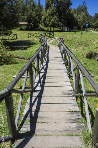 Fototapeta Naklejka Na Ścianę i Meble -  wooden bridge that crosses in an extensive park surrounded by nature. Picnic concept