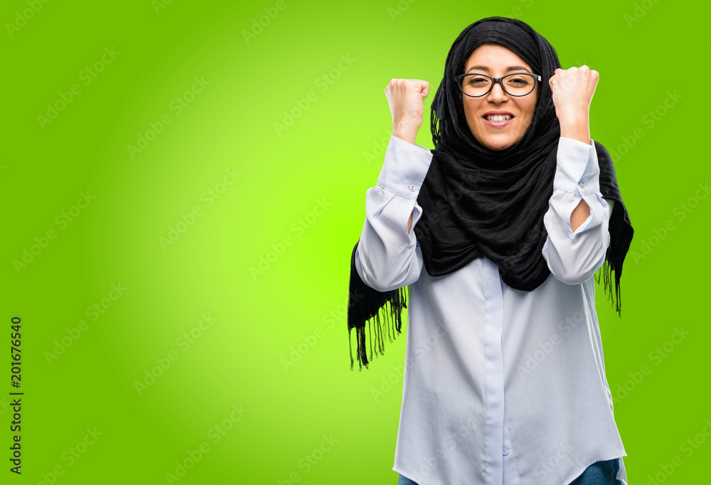 Young arab woman wearing hijab happy and excited celebrating victory expressing big success, power, energy and positive emotions. Celebrates new job joyful Young arab woman wearing hijab happy and excited celebrating victory expressing big success, power, energy and positive emotions. Celebrates new job joyful