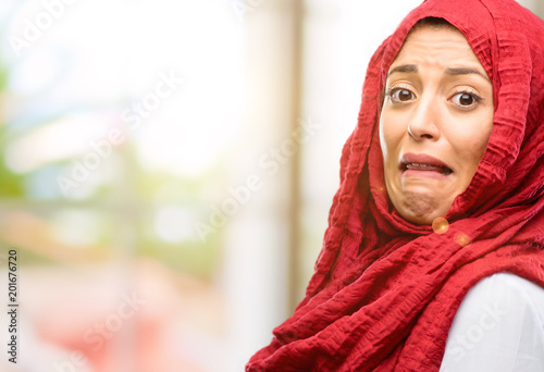 Young arab woman wearing hijab feeling disgusted with tongue out